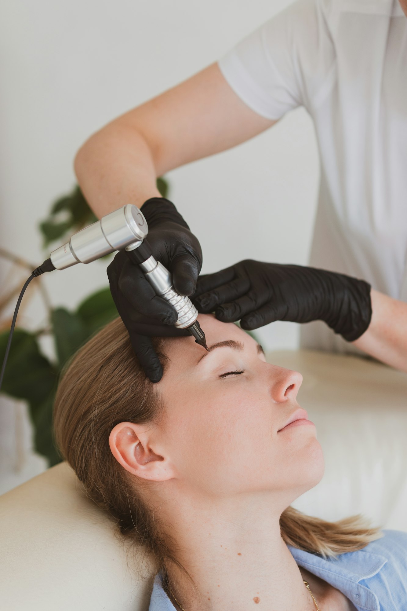 permanent make-up master corrects eyebrows young woman